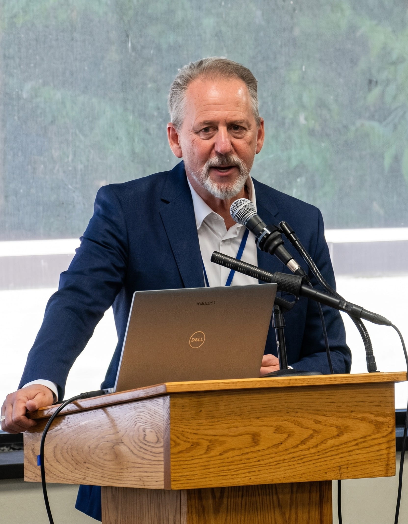 Dr. Joshua Coleman speaking at a podium with microphones and a laptop